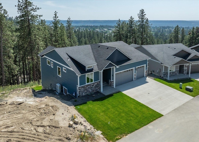 4217 W Tolliver Ct, Spokane, WA 99208 - view of front facade with driveway, a garage, stone siding, a front lawn, and a view of trees