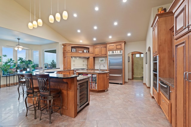 kitchen featuring kitchen peninsula, stainless steel built in refrigerator, beverage cooler, pendant lighting, and a breakfast bar area