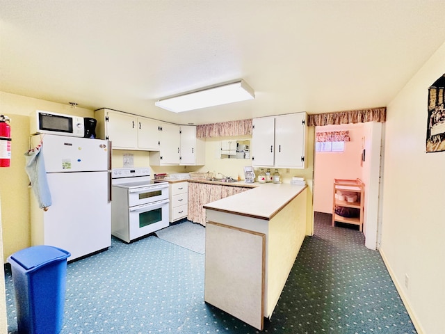 kitchen with kitchen peninsula, sink, white cabinets, and white appliances