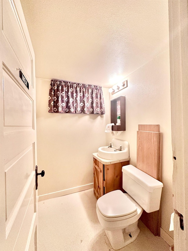 bathroom featuring vanity, toilet, and a textured ceiling