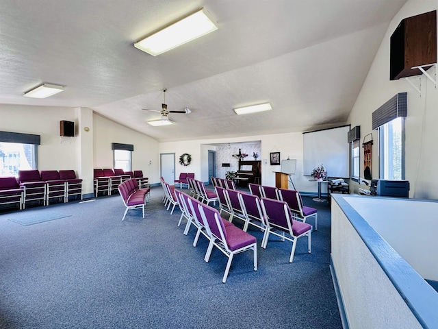 dining space featuring dark colored carpet, ceiling fan, lofted ceiling, and a textured ceiling