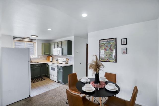 kitchen featuring light carpet, white appliances, backsplash, and sink