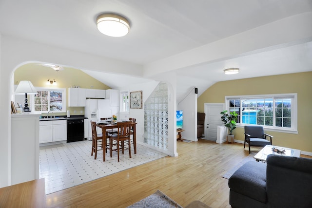 living room with light hardwood / wood-style floors, sink, and vaulted ceiling