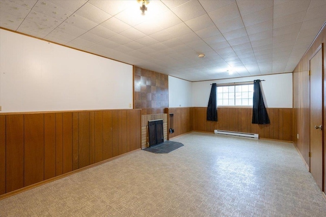 basement with a fireplace, wooden walls, and a baseboard heating unit