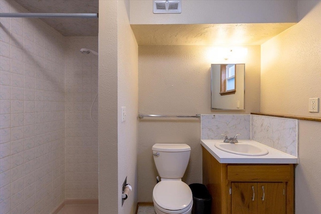 bathroom with tiled shower, decorative backsplash, vanity, and toilet