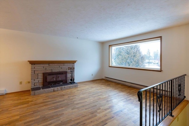 unfurnished living room with a textured ceiling, wood-type flooring, a fireplace, and a baseboard heating unit