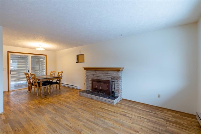 living room with light wood-type flooring, a baseboard radiator, and a wood stove