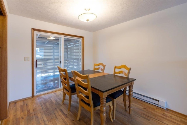 dining room with hardwood / wood-style floors, a textured ceiling, and a baseboard heating unit