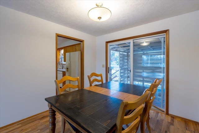 dining area featuring a textured ceiling, hardwood / wood-style flooring, and sink