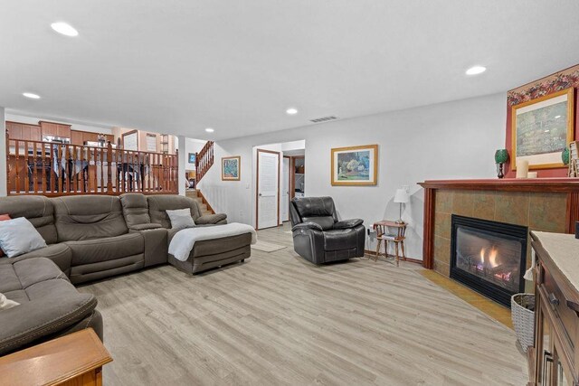 living room featuring light wood-type flooring and a tiled fireplace