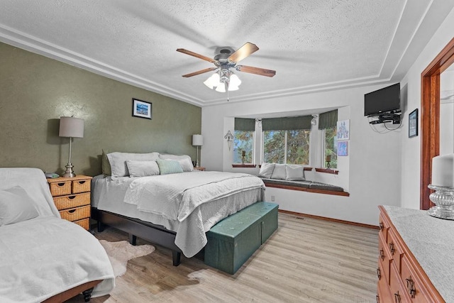 bedroom with ceiling fan, light hardwood / wood-style floors, and a textured ceiling