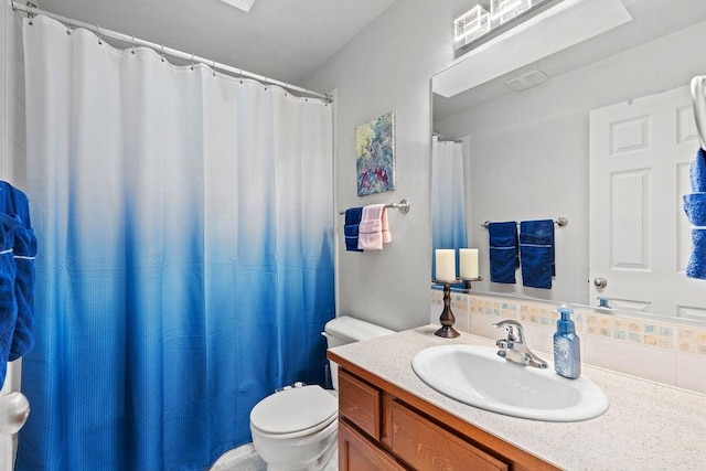 bathroom with vanity, toilet, and tasteful backsplash