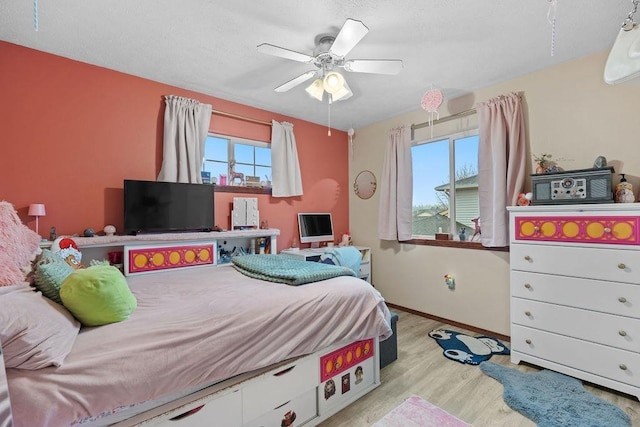 bedroom featuring ceiling fan, multiple windows, and light hardwood / wood-style flooring