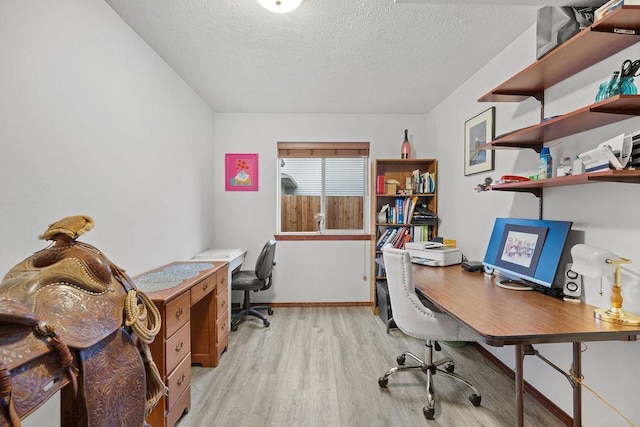 office with light wood-type flooring and a textured ceiling