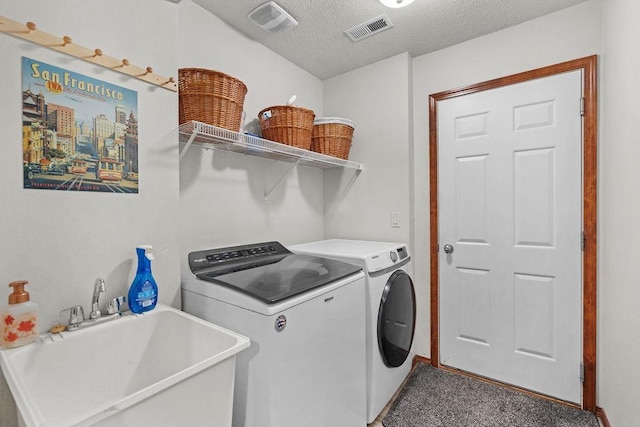 clothes washing area with a textured ceiling, sink, and washing machine and clothes dryer