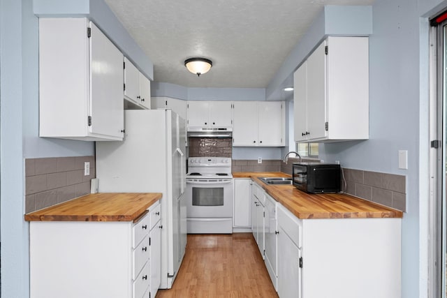 kitchen with tasteful backsplash, white appliances, sink, white cabinetry, and butcher block counters