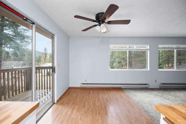 unfurnished room featuring baseboard heating, ceiling fan, and a healthy amount of sunlight