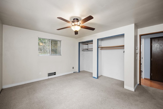 unfurnished bedroom with ceiling fan, light colored carpet, and multiple closets