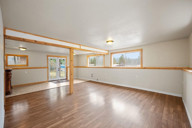 spare room with french doors, plenty of natural light, and wood-type flooring