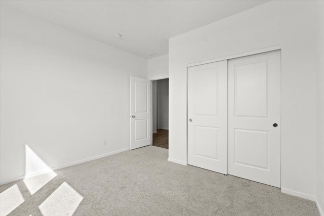 unfurnished bedroom with light carpet and a closet