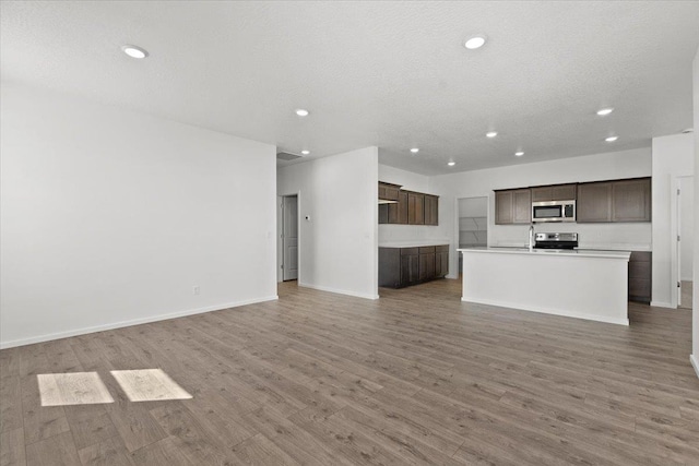 unfurnished living room featuring hardwood / wood-style flooring, sink, and a textured ceiling