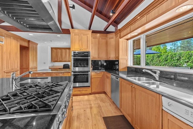 kitchen featuring sink, stainless steel appliances, wall chimney range hood, vaulted ceiling with beams, and light hardwood / wood-style flooring