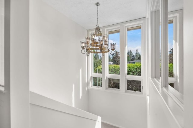 stairs with a textured ceiling and a notable chandelier