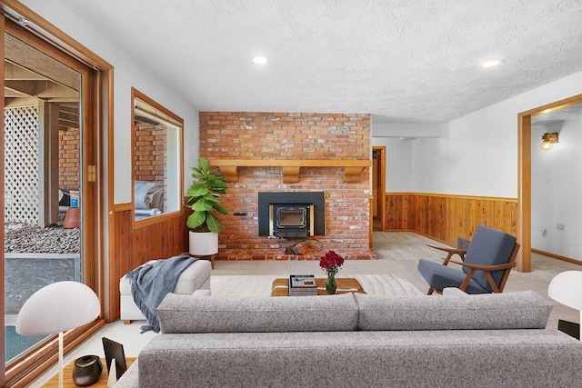 living room with carpet flooring, a wood stove, a textured ceiling, and wooden walls