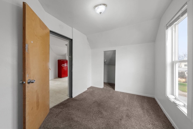 interior space featuring carpet floors, a closet, multiple windows, and lofted ceiling