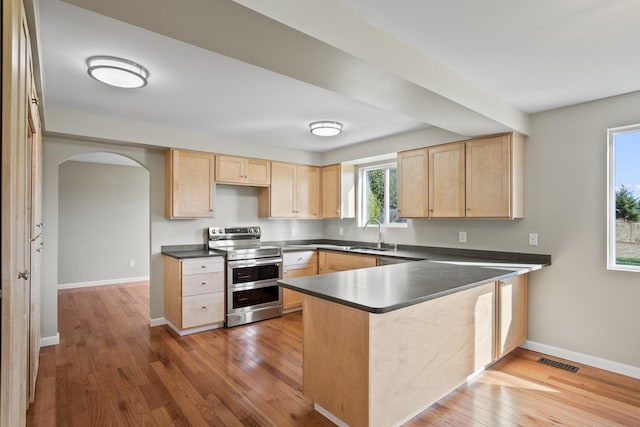 kitchen with hardwood / wood-style floors, stainless steel electric range, kitchen peninsula, and light brown cabinetry