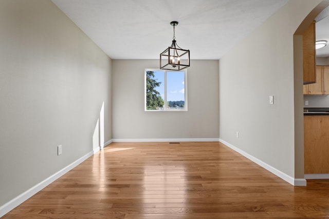 unfurnished dining area with a chandelier and wood-type flooring