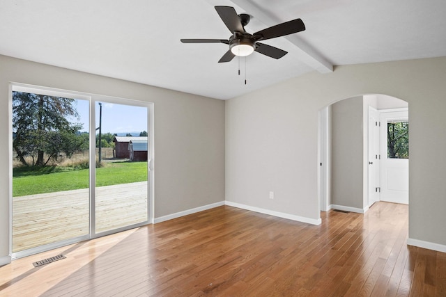 spare room with vaulted ceiling with beams, ceiling fan, a healthy amount of sunlight, and hardwood / wood-style flooring