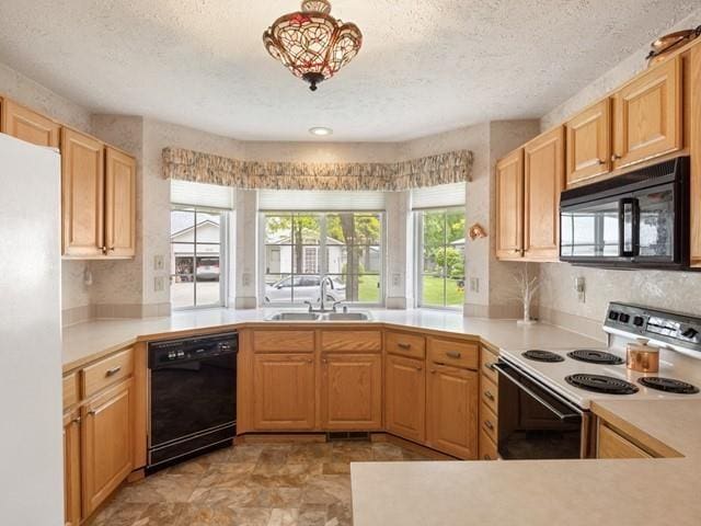 kitchen with kitchen peninsula, a textured ceiling, sink, black appliances, and light brown cabinets