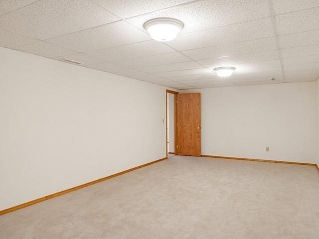 empty room featuring a paneled ceiling and carpet