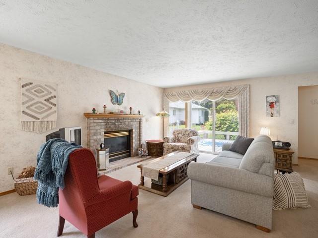 carpeted living room featuring a fireplace and a textured ceiling