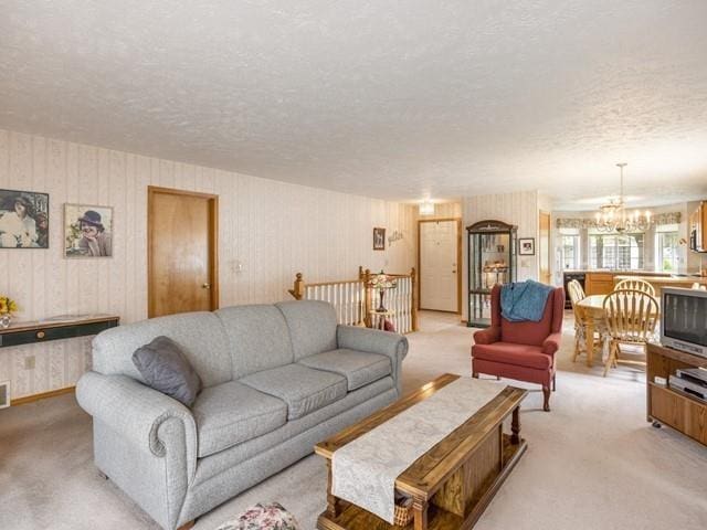 living room featuring light colored carpet, a chandelier, and a textured ceiling