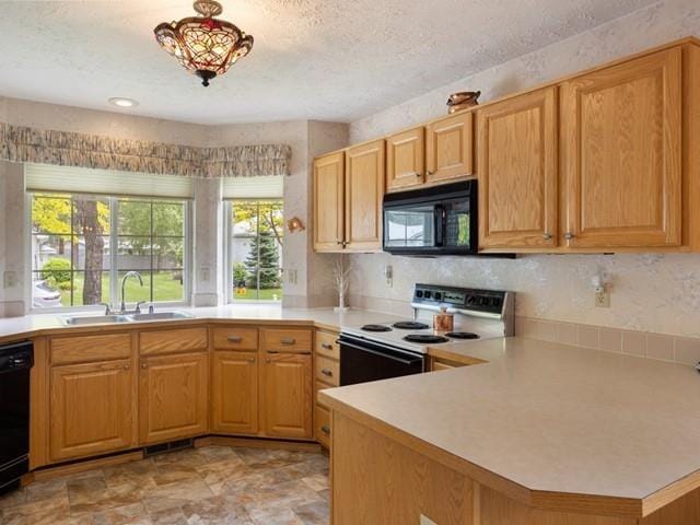 kitchen with kitchen peninsula, sink, black appliances, and a textured ceiling