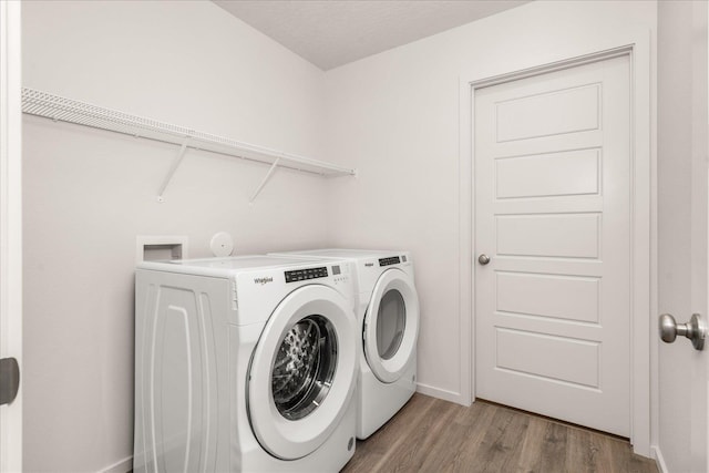 laundry room with a textured ceiling, separate washer and dryer, and light hardwood / wood-style floors