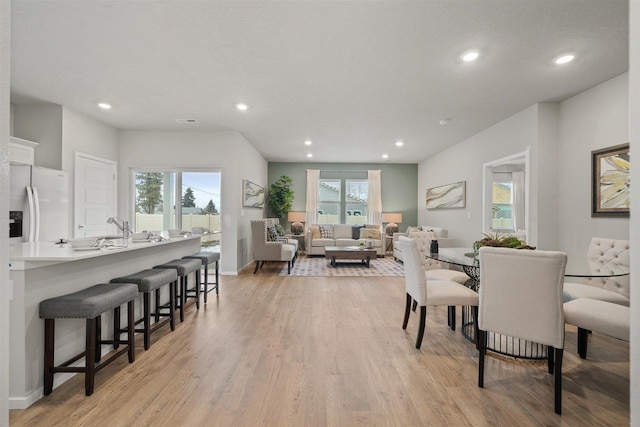 dining space with plenty of natural light, sink, and light hardwood / wood-style flooring