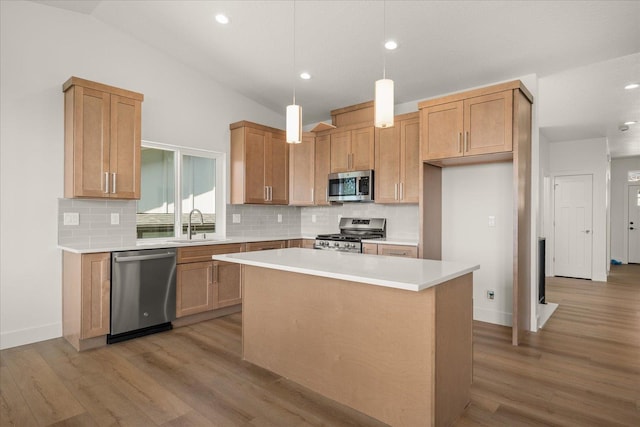 4233 W Tolliver Ct, Spokane, WA 99208 - kitchen featuring appliances with stainless steel finishes, backsplash, light wood-style floors, a kitchen island, and light countertops