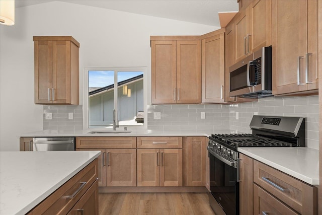 4233 W Tolliver Ct, Spokane, WA 99208 - kitchen featuring appliances with stainless steel finishes, light countertops, backsplash, lofted ceiling, and light wood finished floors