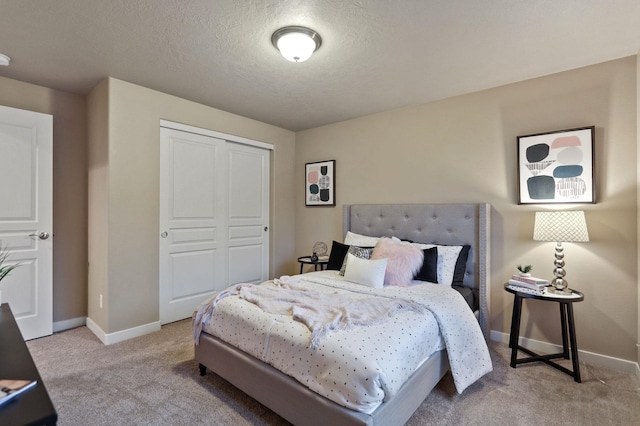 bedroom with a textured ceiling, light colored carpet, and a closet