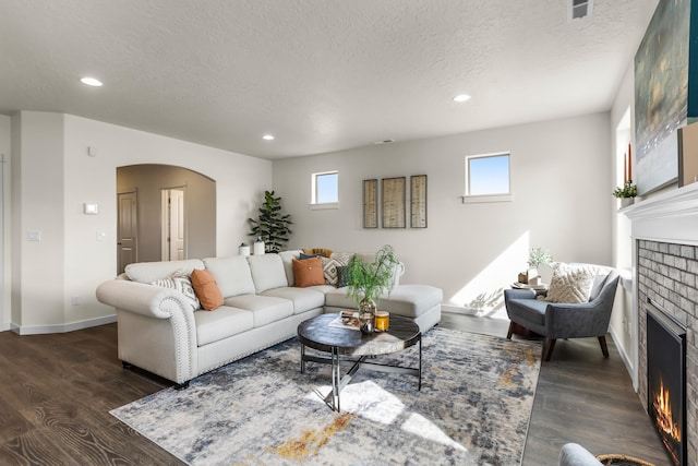 living room featuring a fireplace, a textured ceiling, dark hardwood / wood-style flooring, and a wealth of natural light