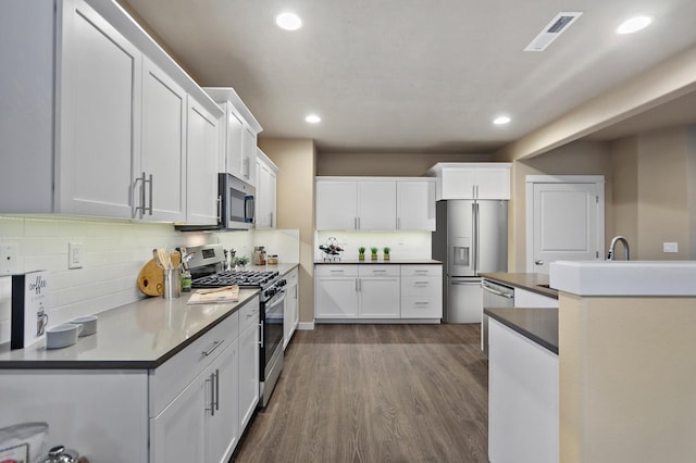 kitchen with decorative backsplash, dark hardwood / wood-style flooring, stainless steel appliances, and white cabinetry