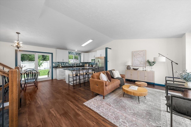 living room with dark hardwood / wood-style flooring, lofted ceiling, a textured ceiling, and an inviting chandelier