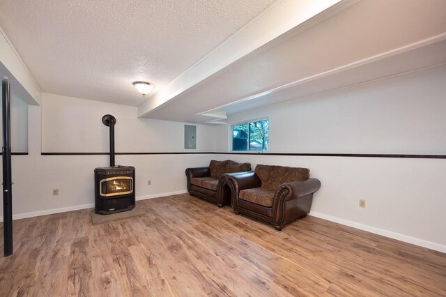 sitting room with hardwood / wood-style flooring, a wood stove, and a textured ceiling