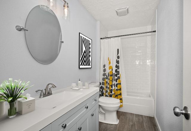 full bathroom with hardwood / wood-style flooring, vanity, toilet, shower / bath combo, and a textured ceiling