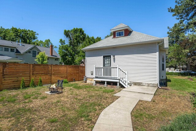 back of property with a lawn and a fire pit