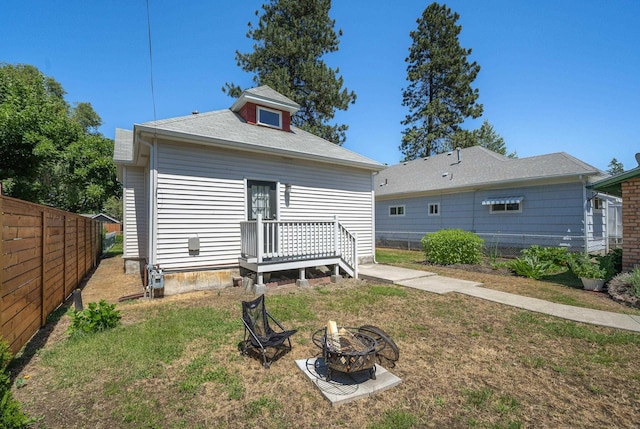 rear view of property with an outdoor fire pit and a yard