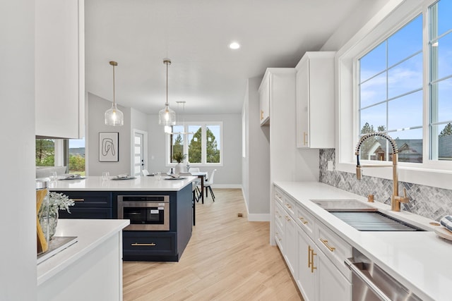 kitchen with appliances with stainless steel finishes, sink, white cabinets, backsplash, and hanging light fixtures